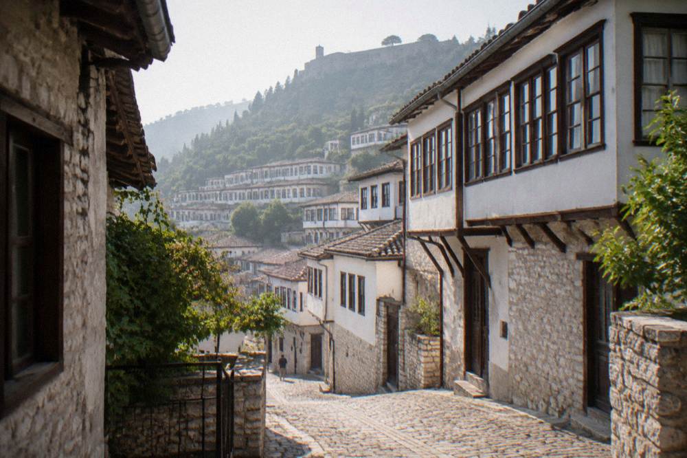 A cobbled lane of white Ottoman houses stacked on a hillside in Berat's Mangalem quarter