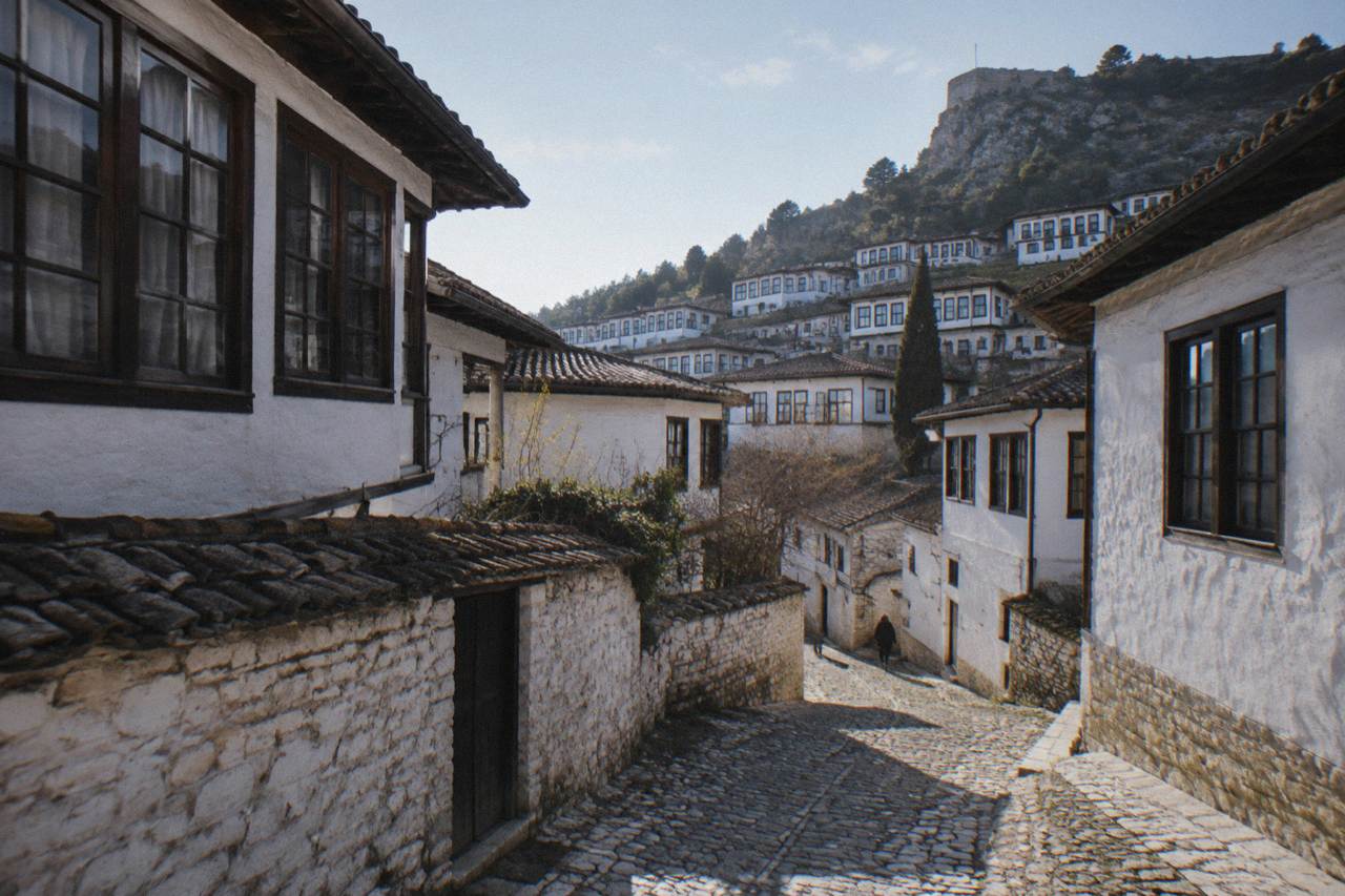 A cobbled lane of white Ottoman houses stacked on a hillside in Berat's Mangalem quarter