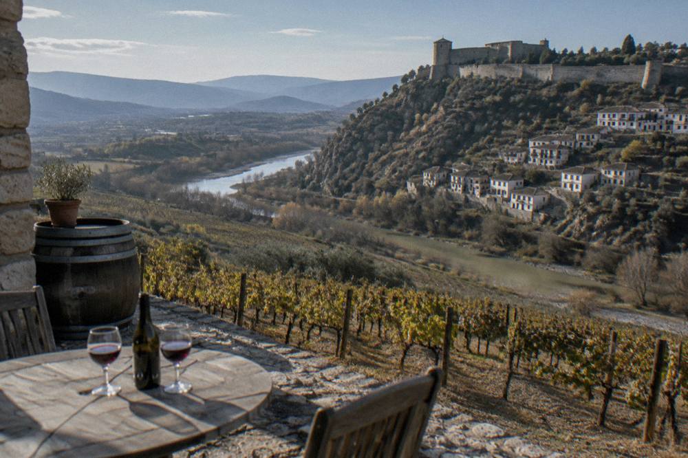A stone winery terrace overlooking rows of vines on hillsides near Berat
