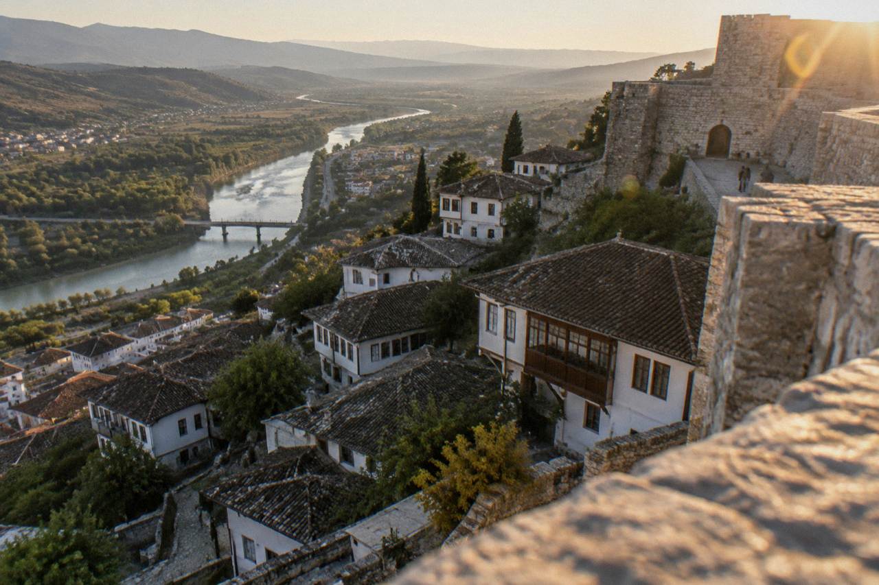 Whitewashed Ottoman houses stacked on a hillside below the stone walls of Berat Castle