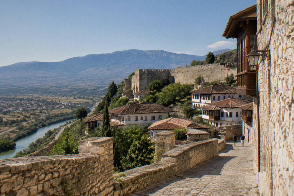 Stone lane in Berat castle quarter with a mountain ridge visible in the distance