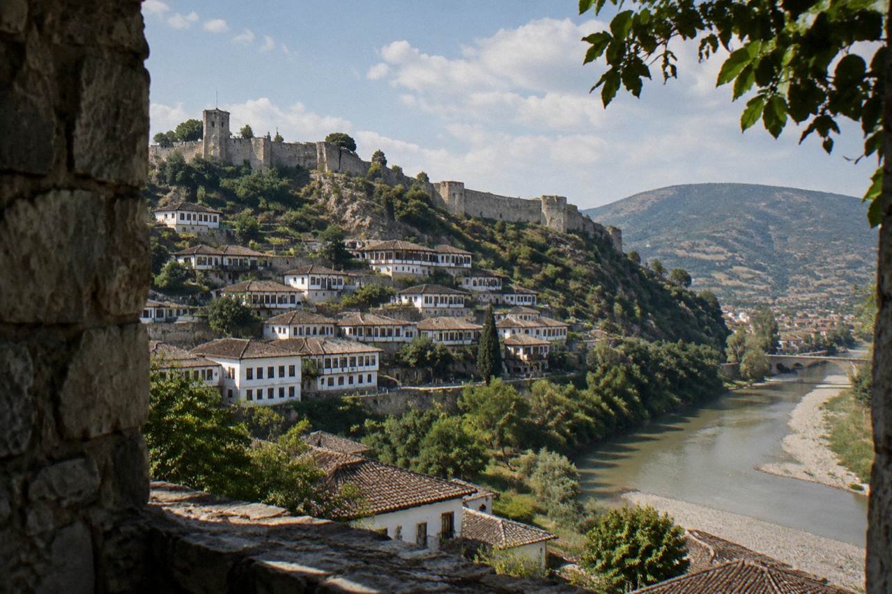 White Ottoman houses stacked on a hillside above a river in Berat, Albania