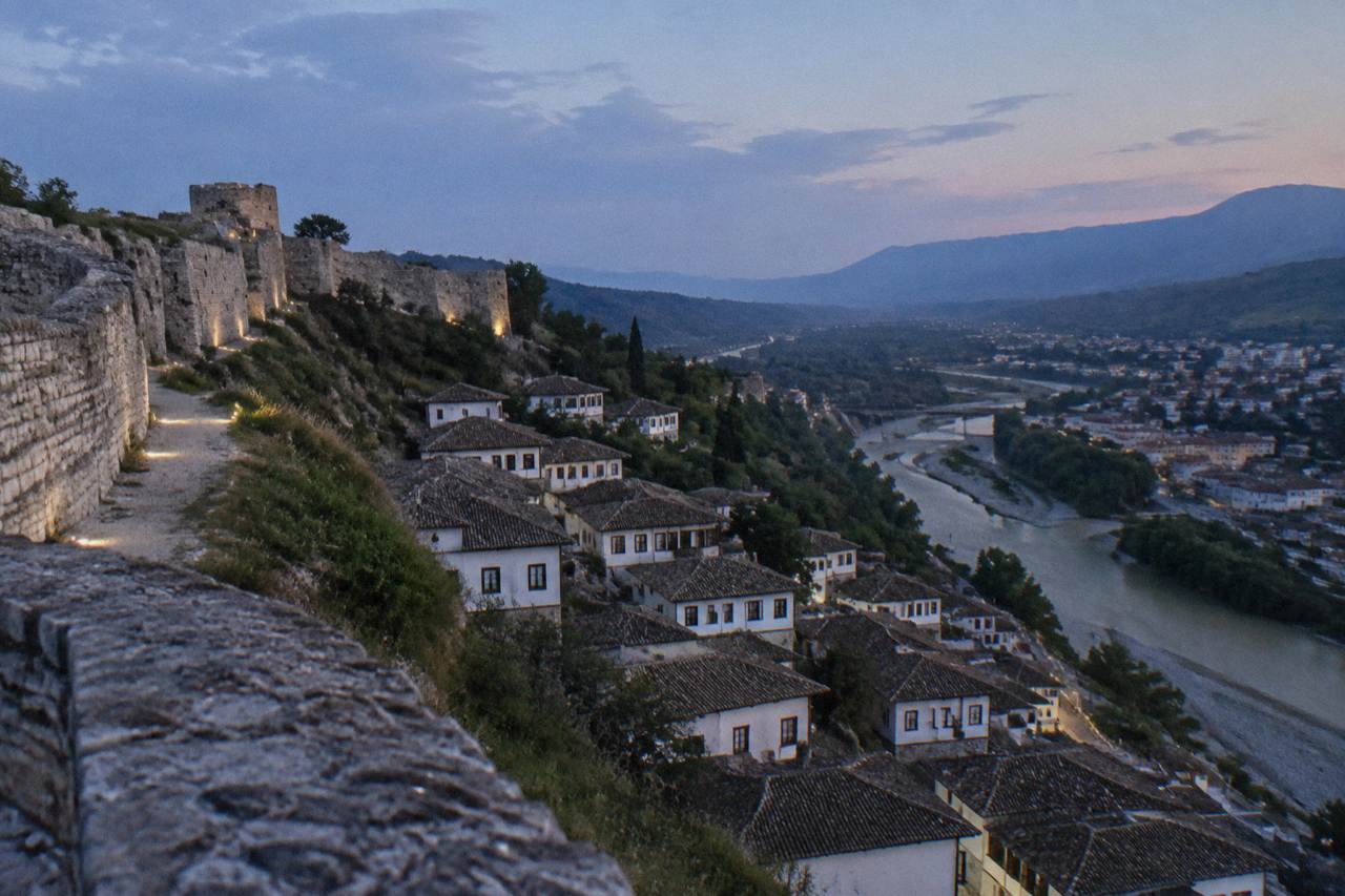 White Ottoman houses stacked on a hillside above a river in Berat, Albania