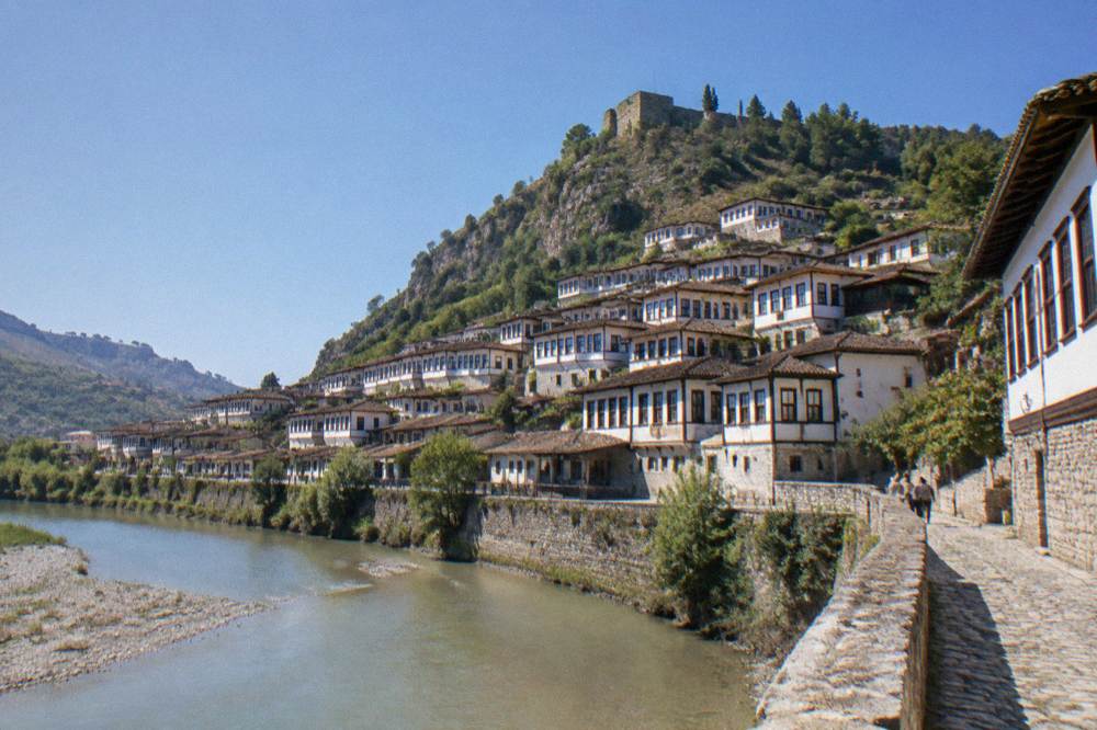 White Ottoman houses of Mangalem stacked on a hillside above the Osum River in Berat