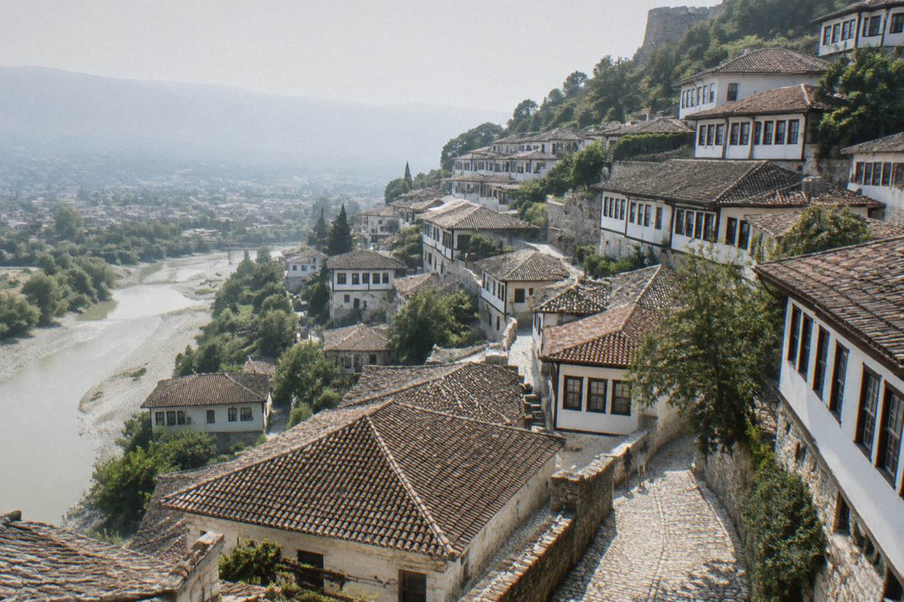 White Ottoman houses of Mangalem stacked on a hillside above the Osum River in Berat