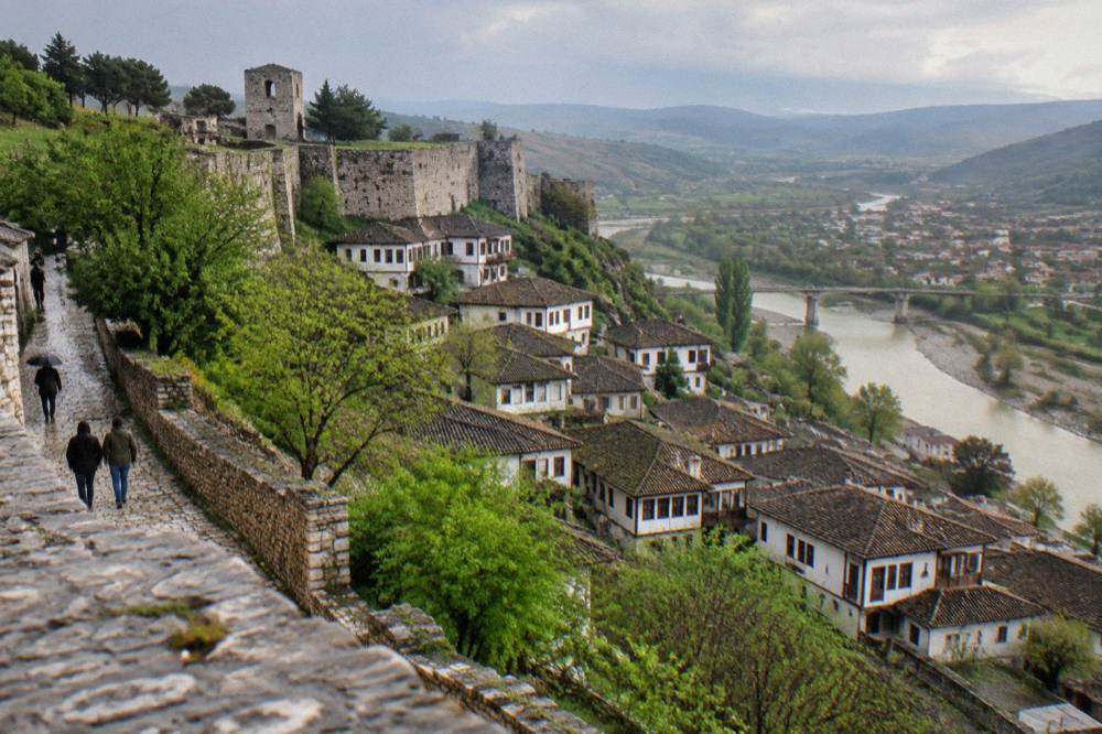 White Ottoman houses of Berat stacked on a hillside above the Osum River in spring