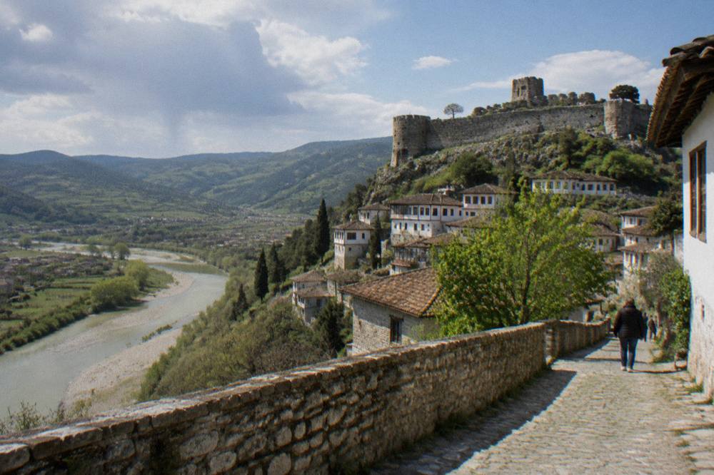 Green spring hills above the Osum River with stone walls and a distant castle