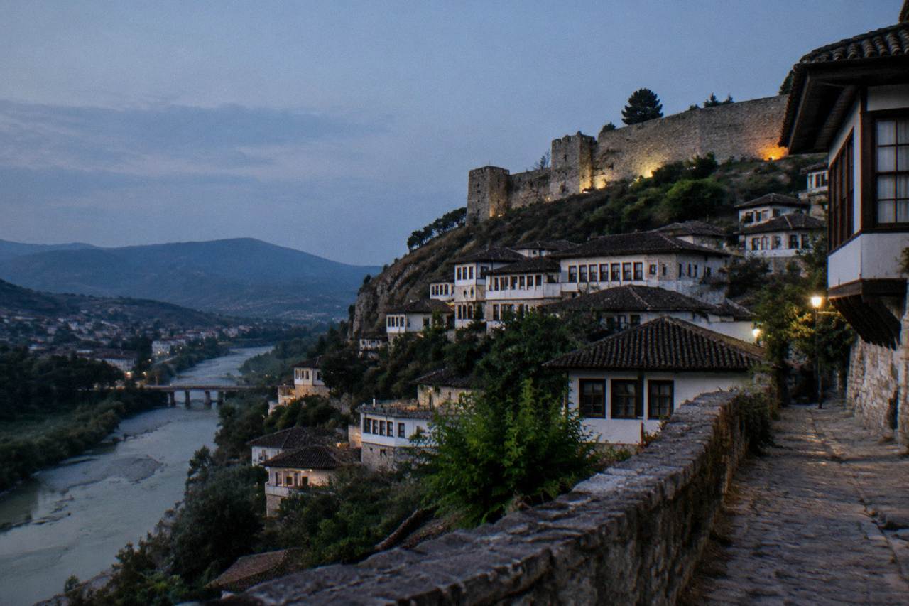 White Ottoman houses stacked on a hillside above a river in Berat, Albania
