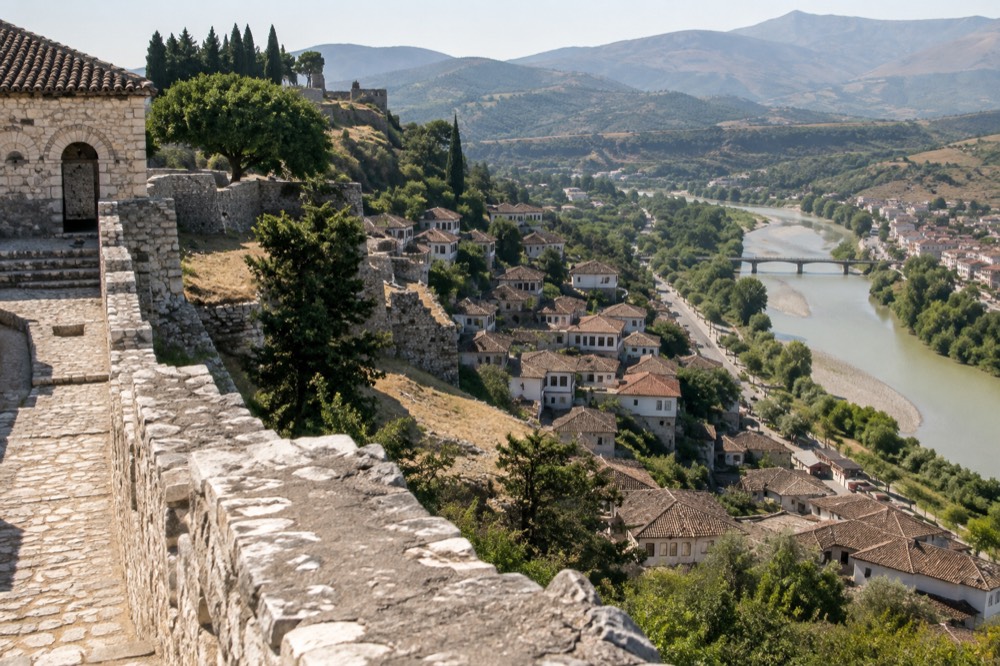 White Ottoman houses stacked on a hillside above a river in Berat, Albania