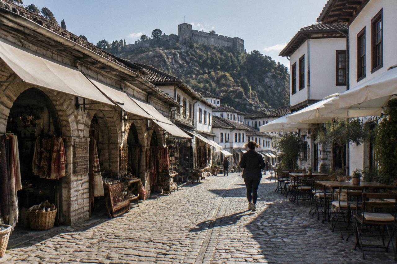 A stone street in Berat old town with cafe tables set out beside whitewashed Ottoman houses