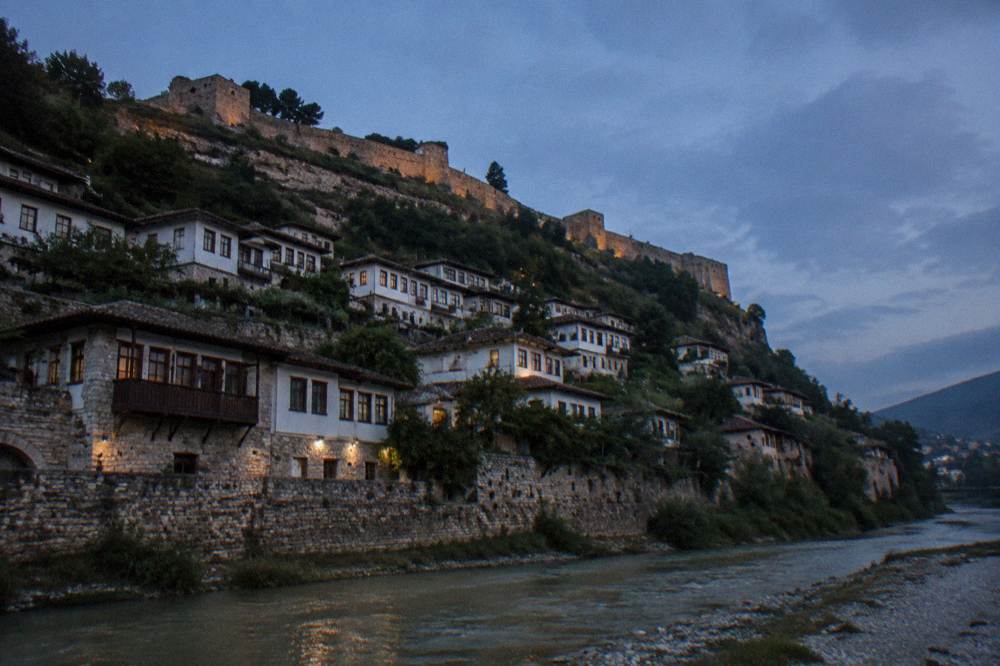 The Osum River flowing beneath stone houses stacked on a hillside in Berat