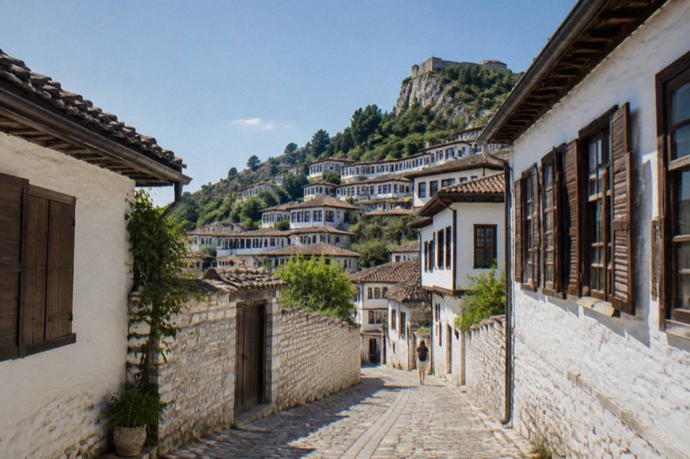 A narrow stone lane between whitewashed houses with wooden shutters