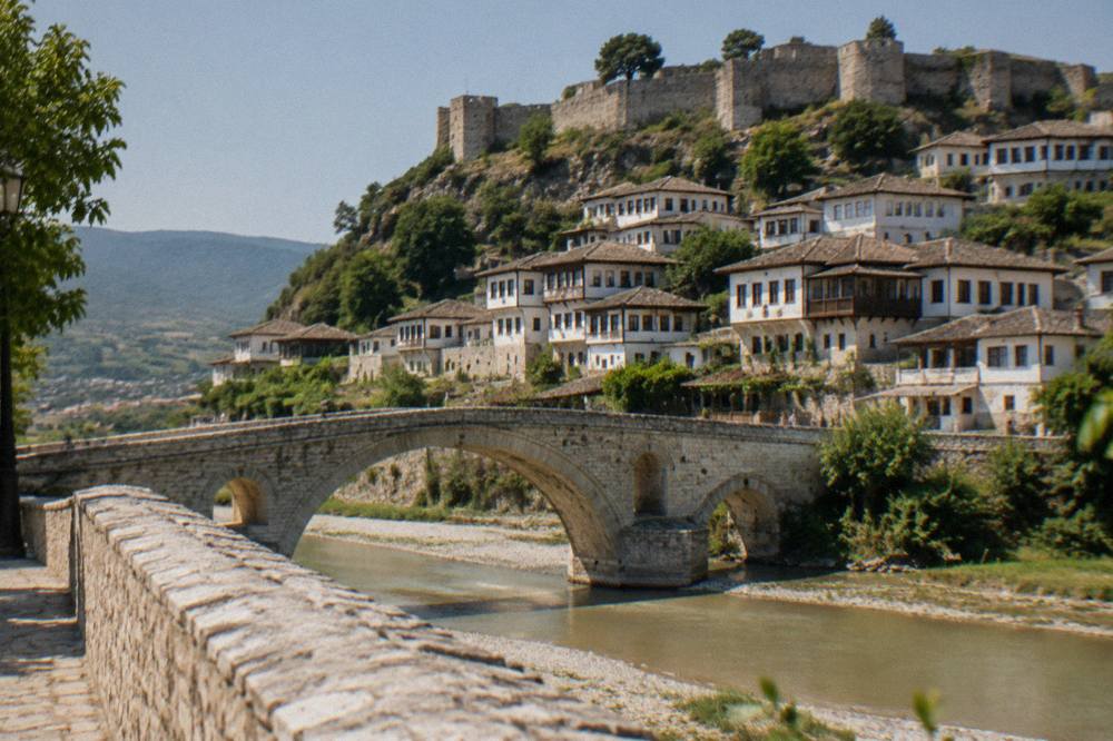 Stone bridge over a river with white hillside houses behind it