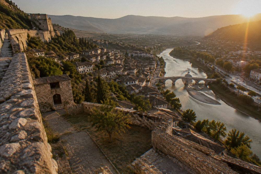 A stone bridge over the Osum River connecting Berat's lit old quarters at dusk