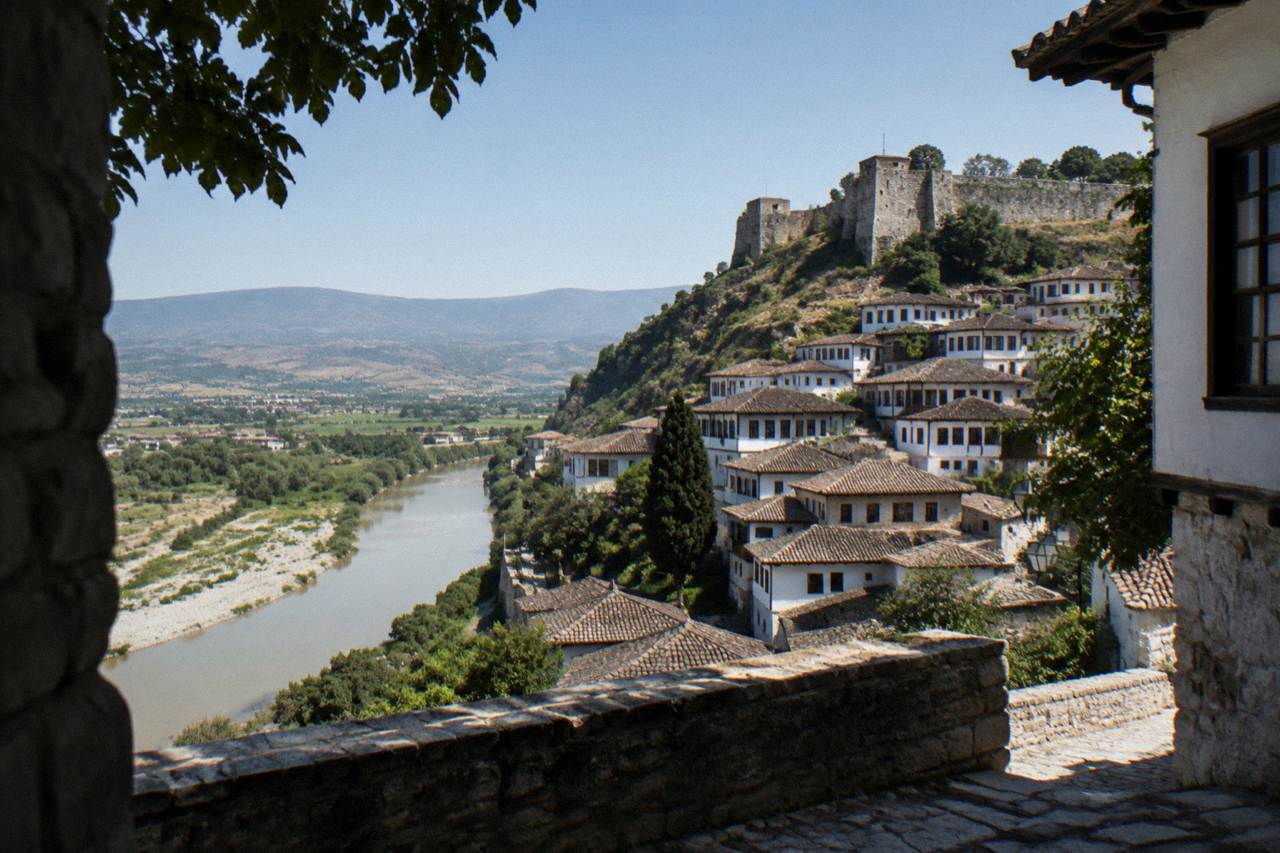 White Ottoman houses stacked on a hillside above a calm river in Berat, Albania