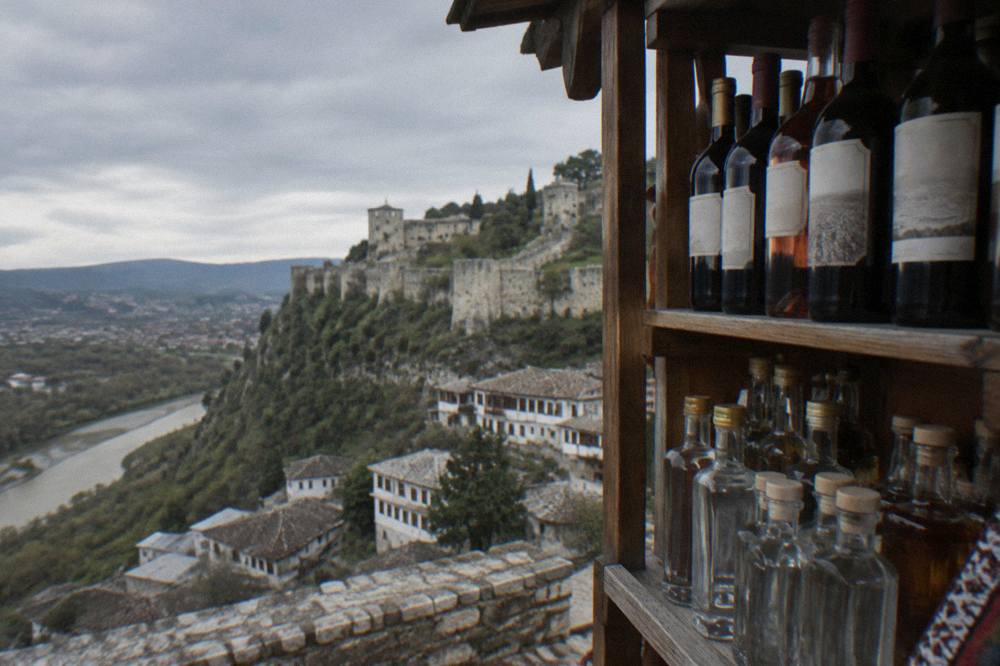 Bottles of local Albanian wine and raki on a wooden shop shelf in Berat