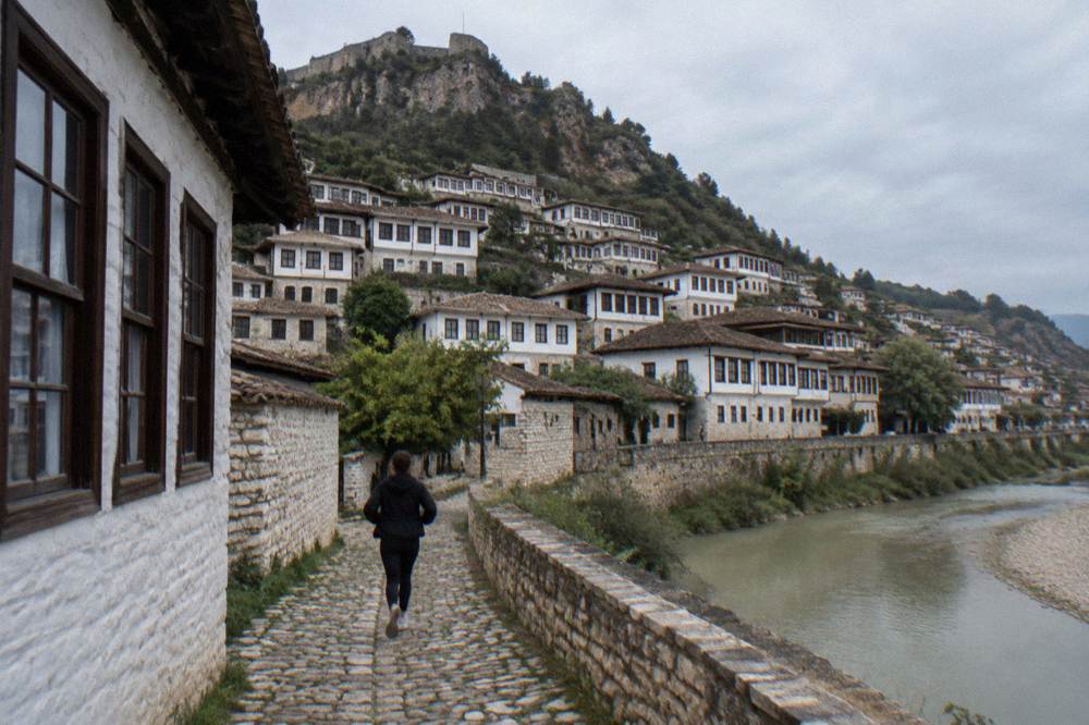 White Ottoman houses of Mangalem stacked on a hillside above the Osum River in Berat