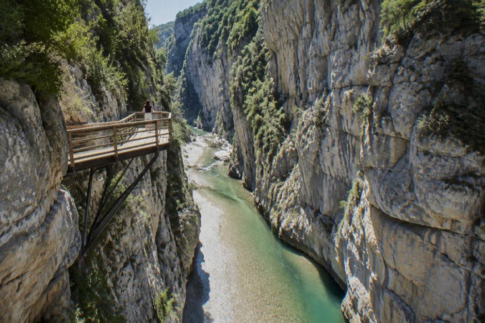 Steep limestone walls of Osumi Canyon rising above green river water in the Skrapar region
