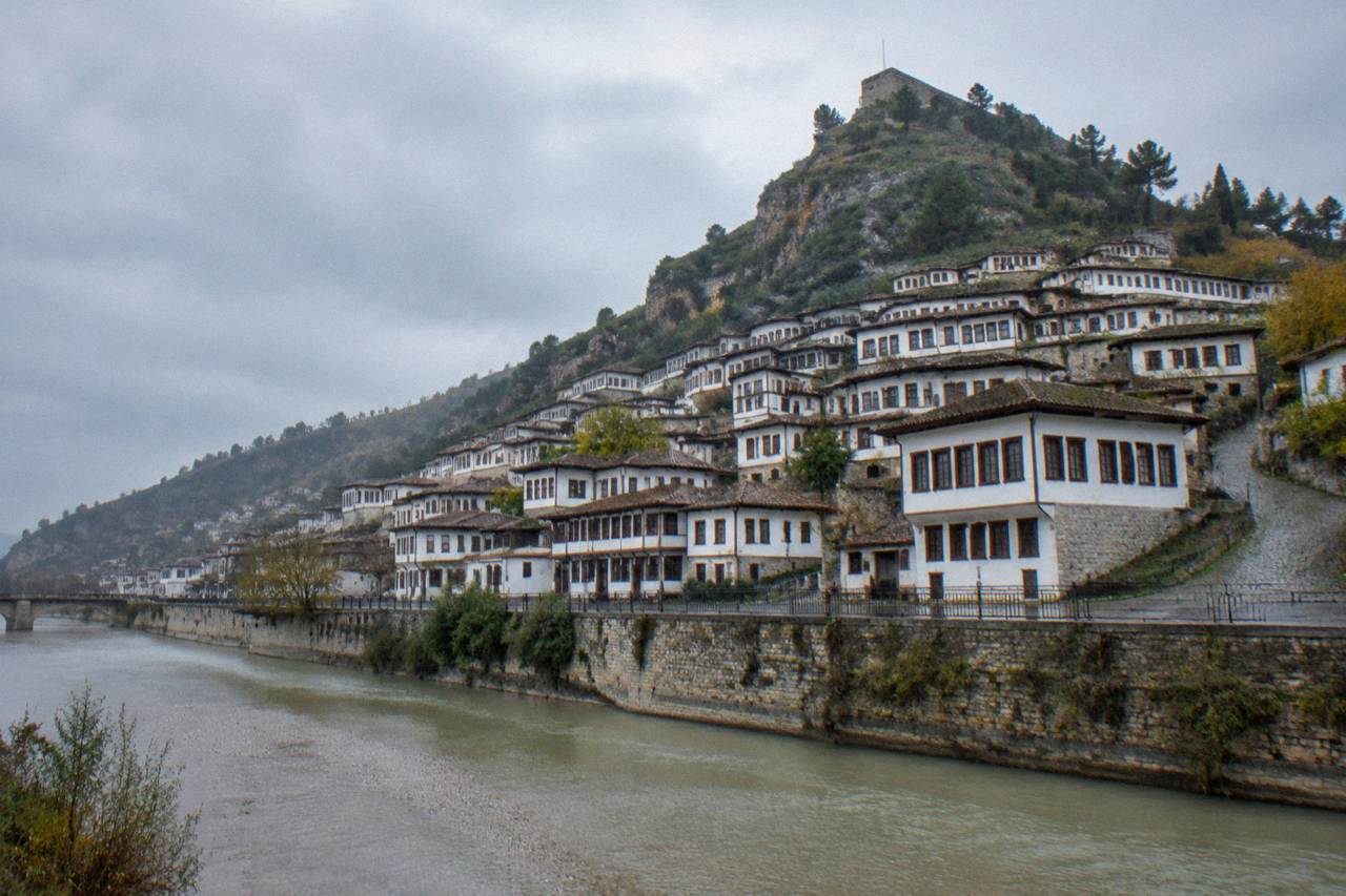 White Ottoman houses of Mangalem stacked on a hillside above the Osum River in Berat