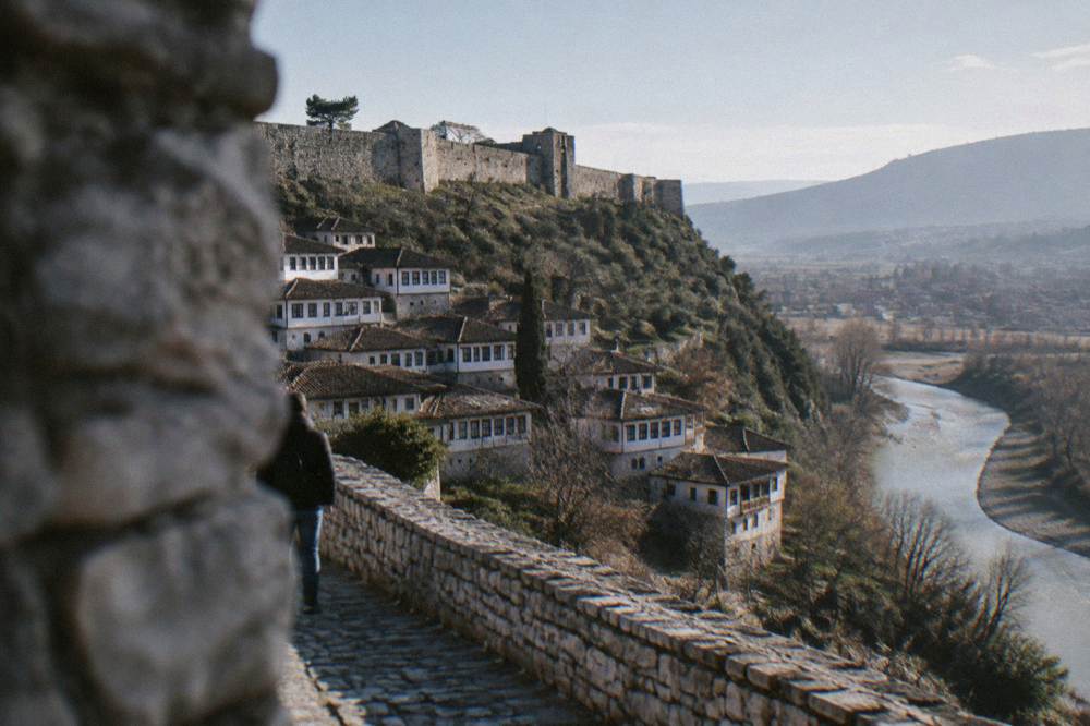 White Ottoman houses stacked on a hillside above a river in Berat