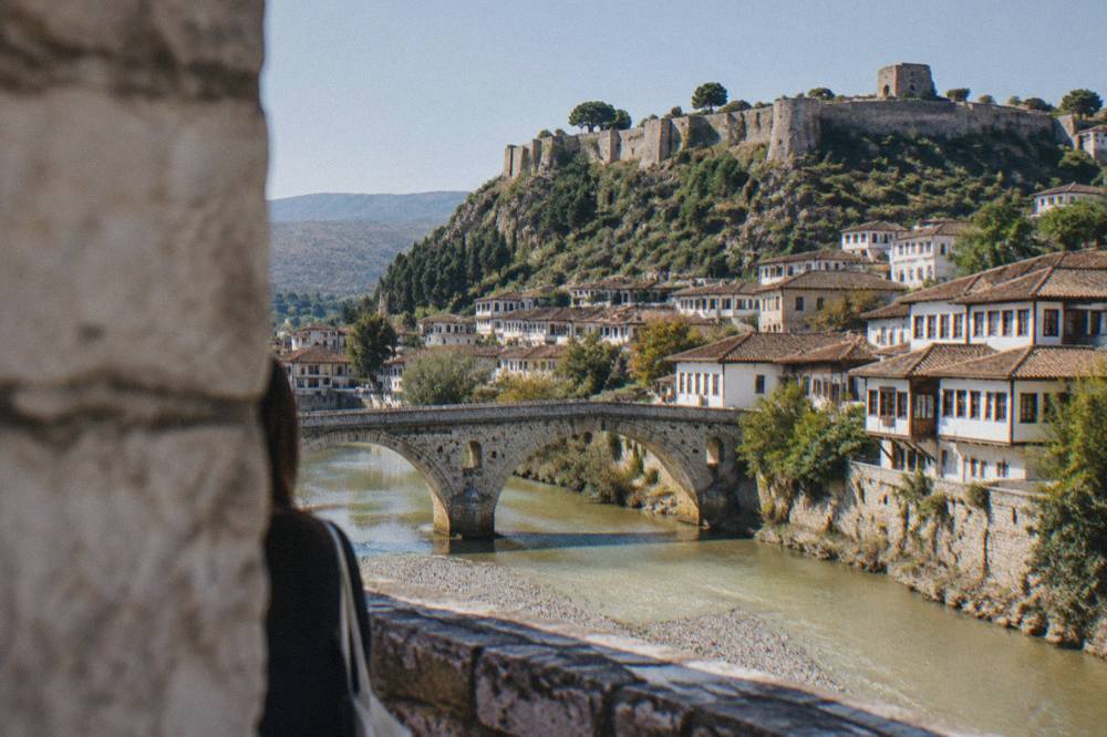 A stone bridge over the Osum River with old houses rising on both banks in Berat