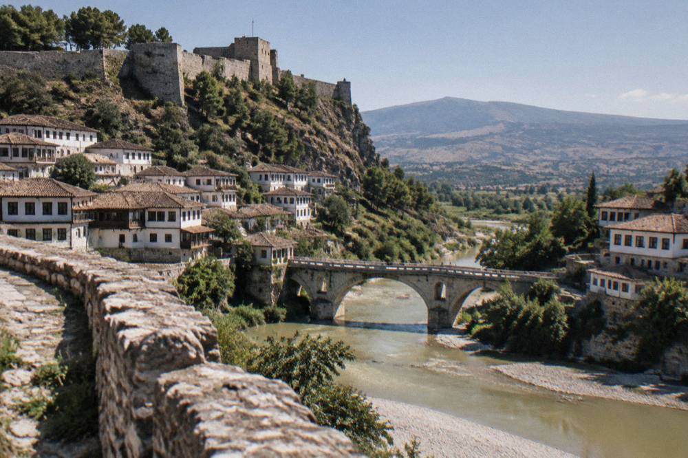 Steep limestone canyon walls rising above a green river in the Albanian countryside