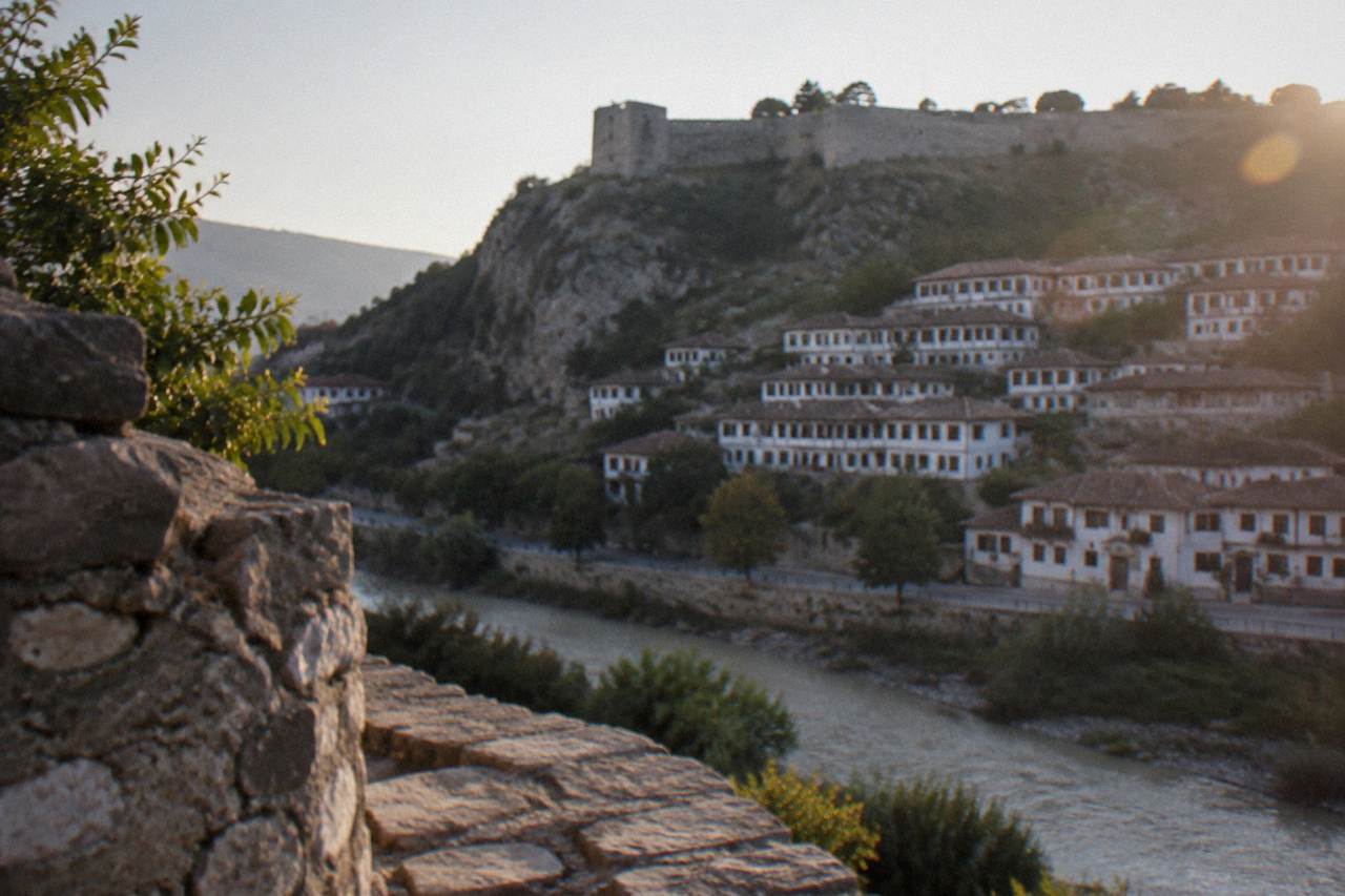 White Ottoman houses stacked on a hillside above a river in Berat