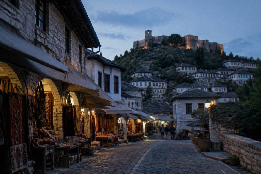 Stone buildings of Gjirokaster's old town with slate roofs rising toward the fortress