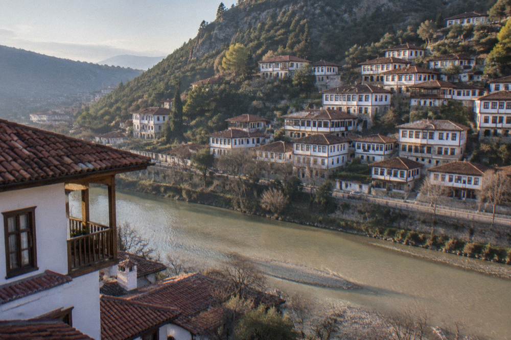 Red-roofed Ottoman houses stacked on a green hillside above a wide river