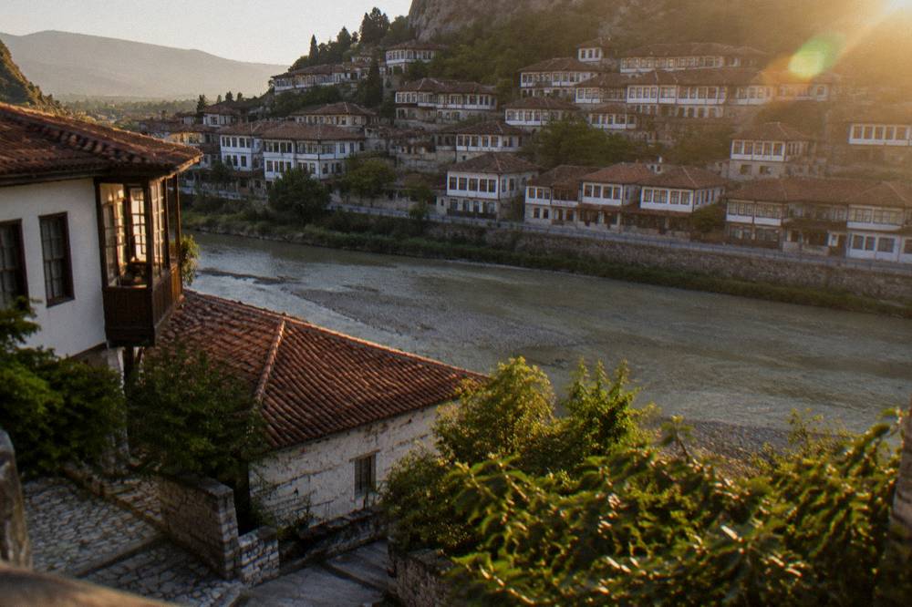 White Ottoman houses with many windows glowing in low sun across a river