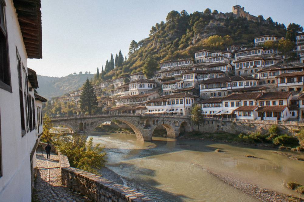An old stone bridge over a river with white hillside houses on both banks