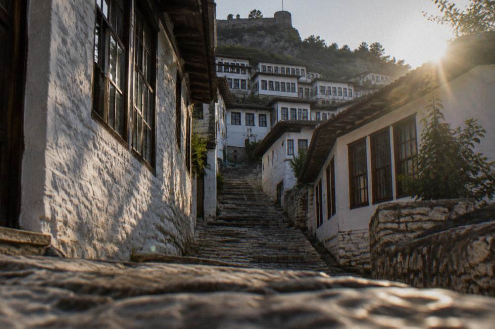 A steep stone staircase between whitewashed houses with wooden window frames