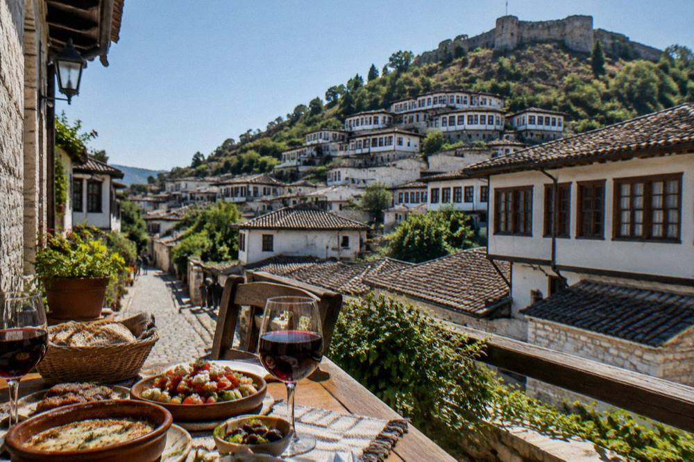A table with traditional Albanian food and glasses of local red wine on a terrace