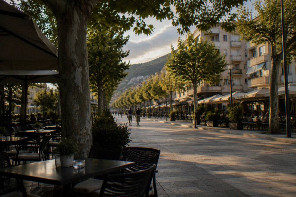 Cafe tables and trees along a pedestrian street in evening light