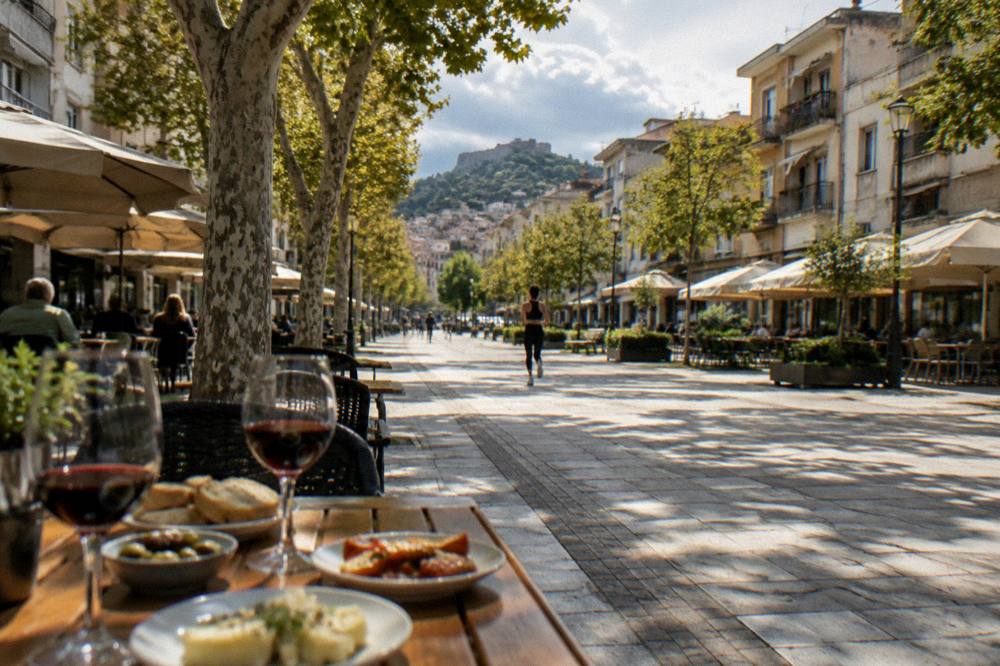 Outdoor restaurant table with small plates of food and glasses of red wine