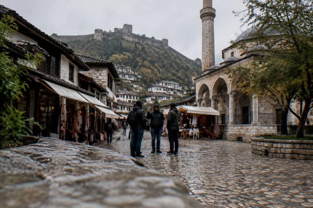 Guide speaking to a small group on a cobbled square beside an old mosque