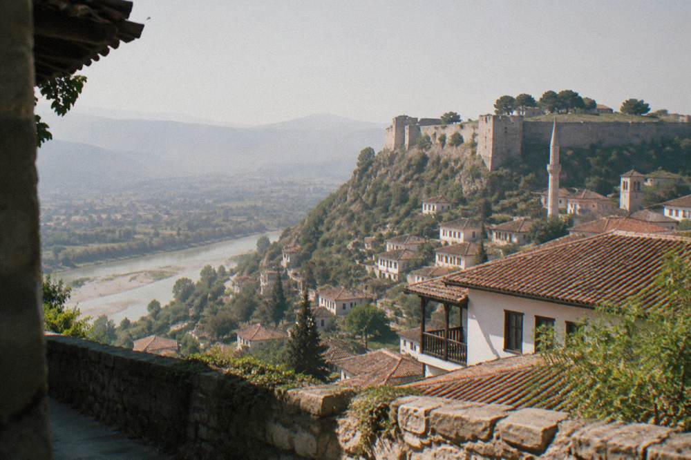 Stone minaret and church tower sharing the skyline above the red-tiled roofs of Berat