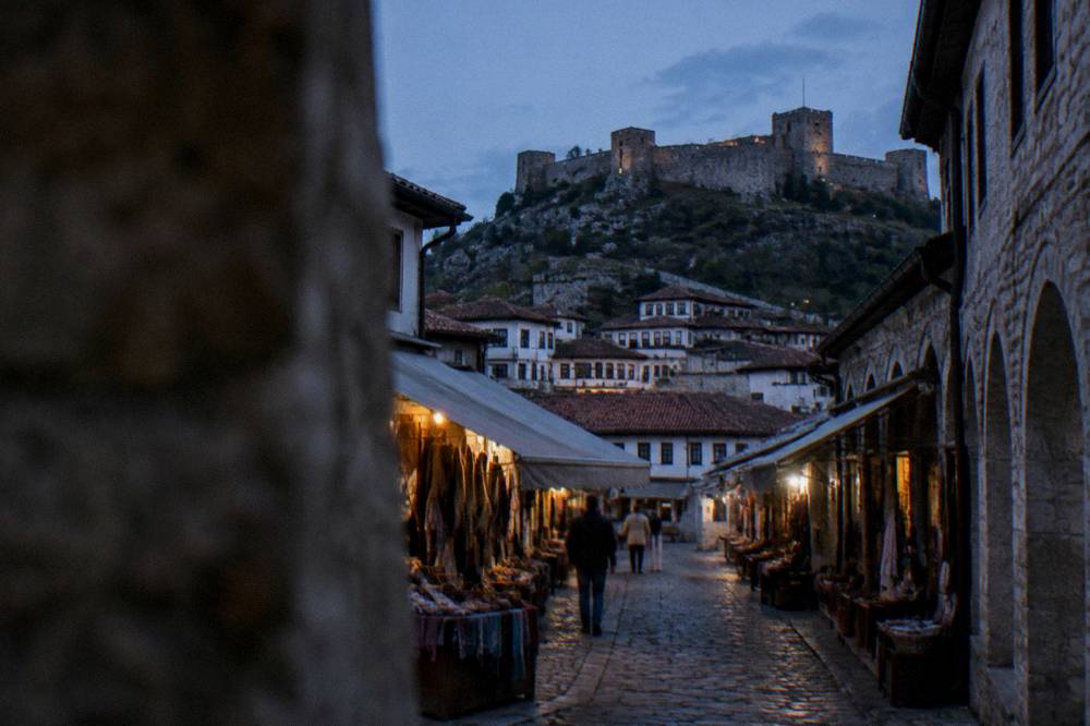 Ancient stone castle walls and towers on a hill above the tiled roofs of Berat old town