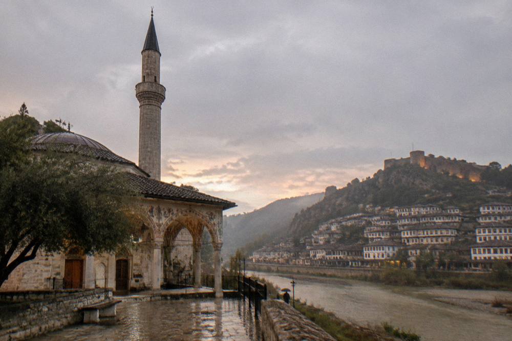 Long distance view of Berat's white hillside houses, the river and the castle above in evening light