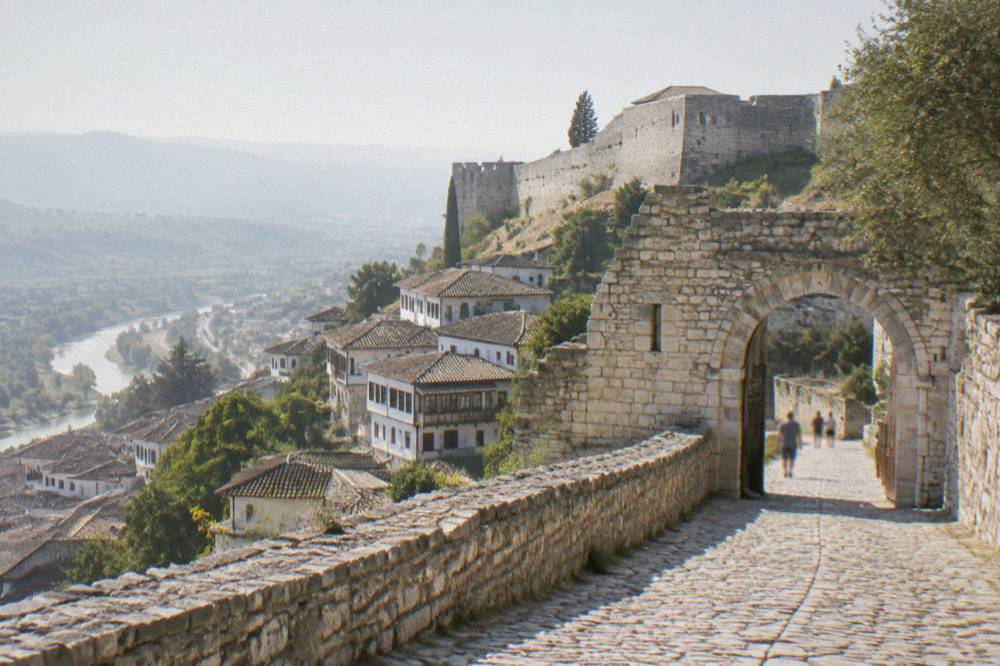 Stone gate and cobbled road climbing toward a hilltop fortress