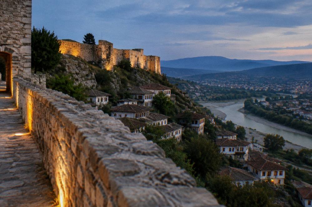 Golden evening light on a stone fortress wall above a river valley