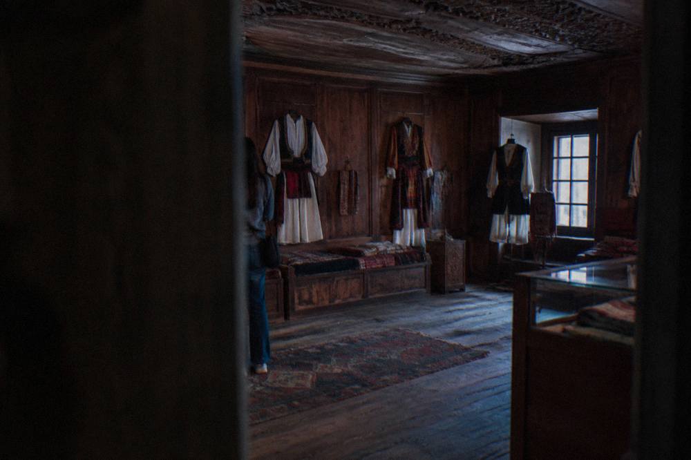 Display of woven textiles and traditional folk costumes laid out in a wood-panelled museum room