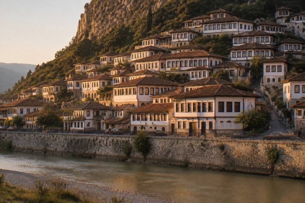 Evening light on the white walls and red-tiled roofs of the Mangalem hillside seen from across the river