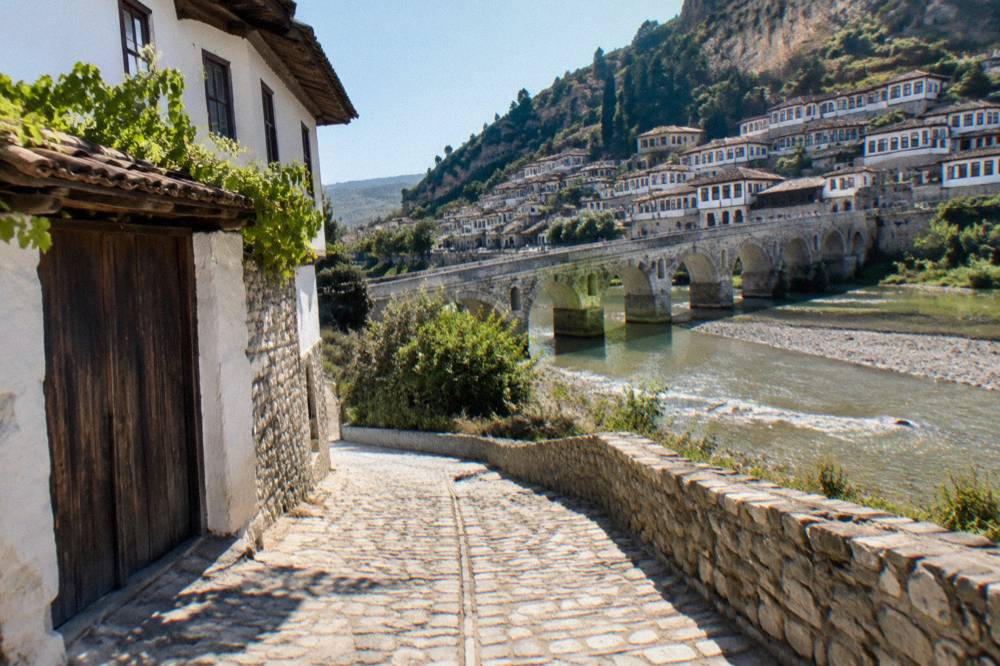 Narrow stone-paved lane on a hillside bank with whitewashed houses and wooden gates