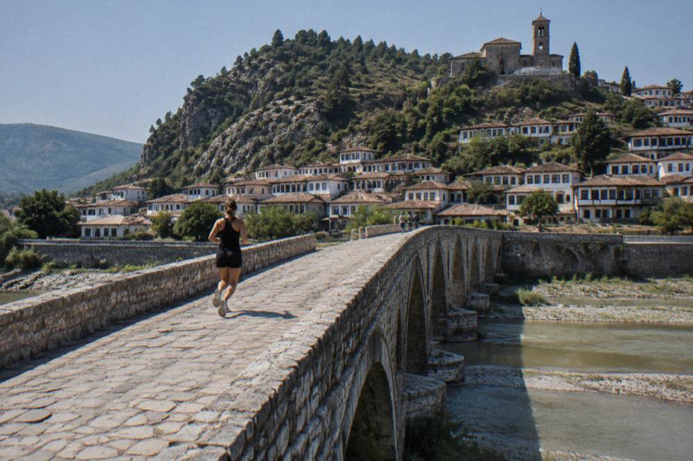 Small stone church with a bell tower standing above the roofs of a riverside town