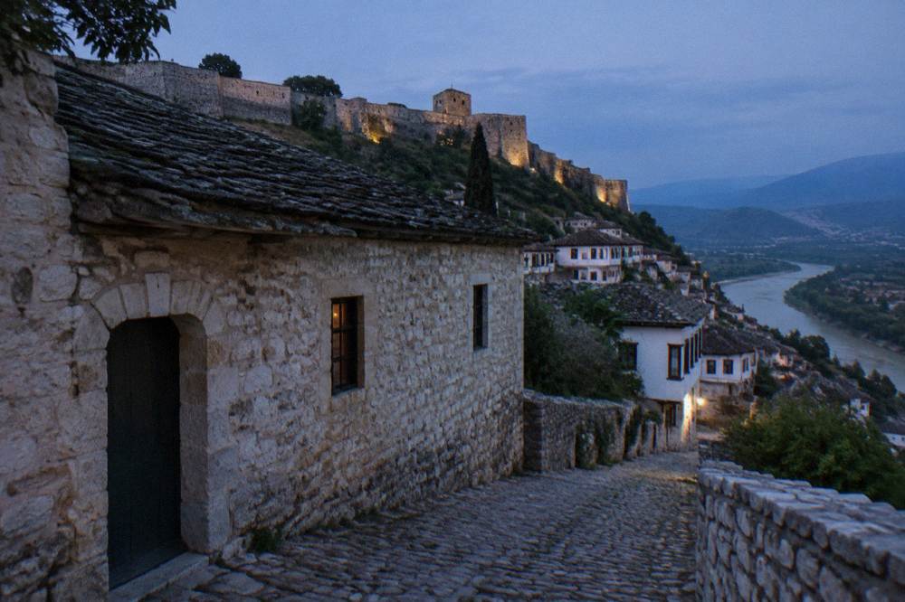 A stone tekke building with a low door and small windows on a cobbled lane in Berat