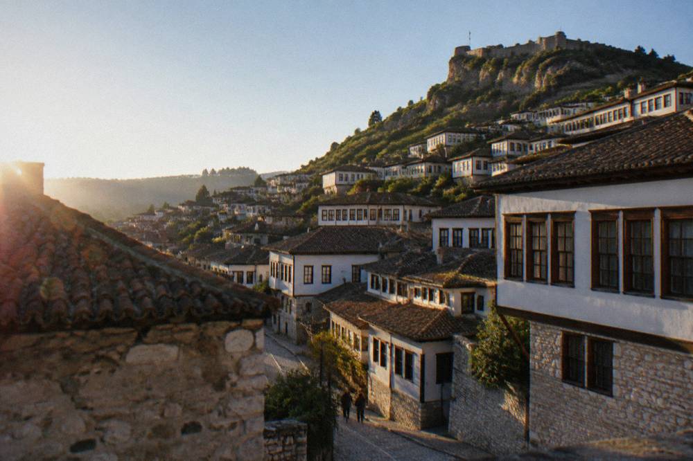 White Ottoman houses on the Mangalem hillside under a clear morning sky
