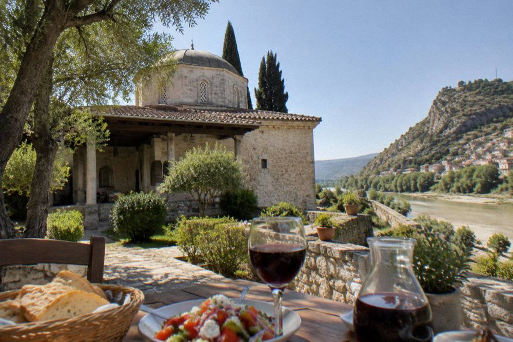 A modest restaurant table with bread, salad and local wine on a terrace above the river