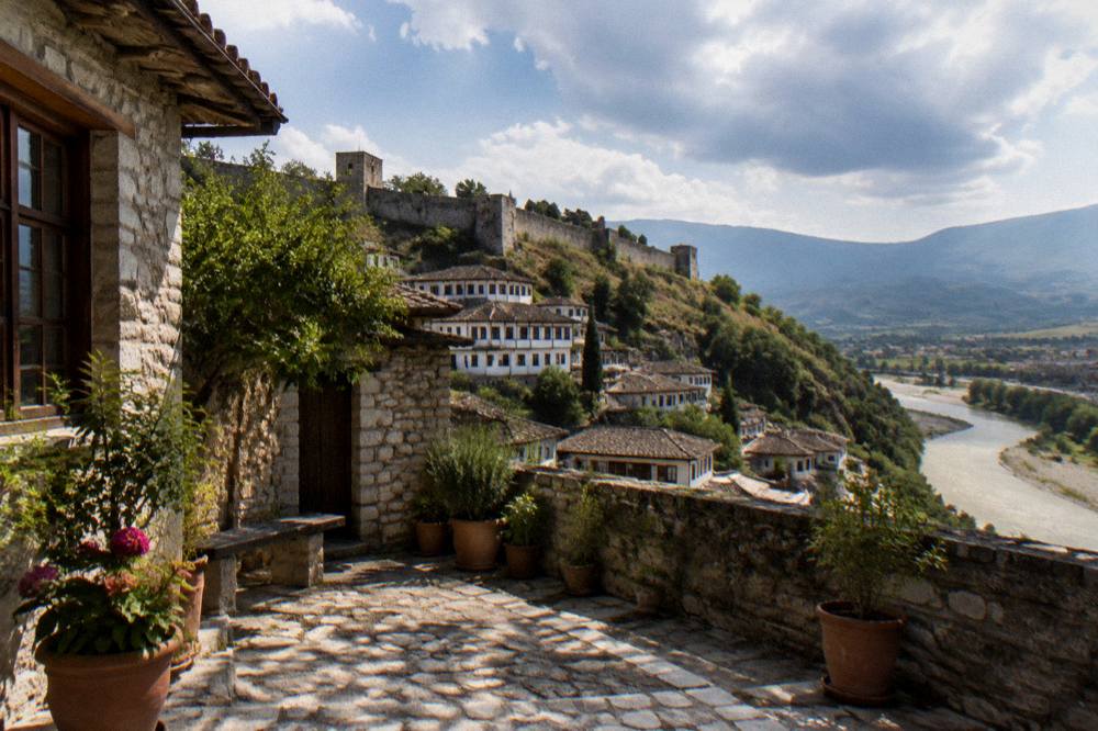 A quiet courtyard with stone walls and potted plants outside an old Berat house