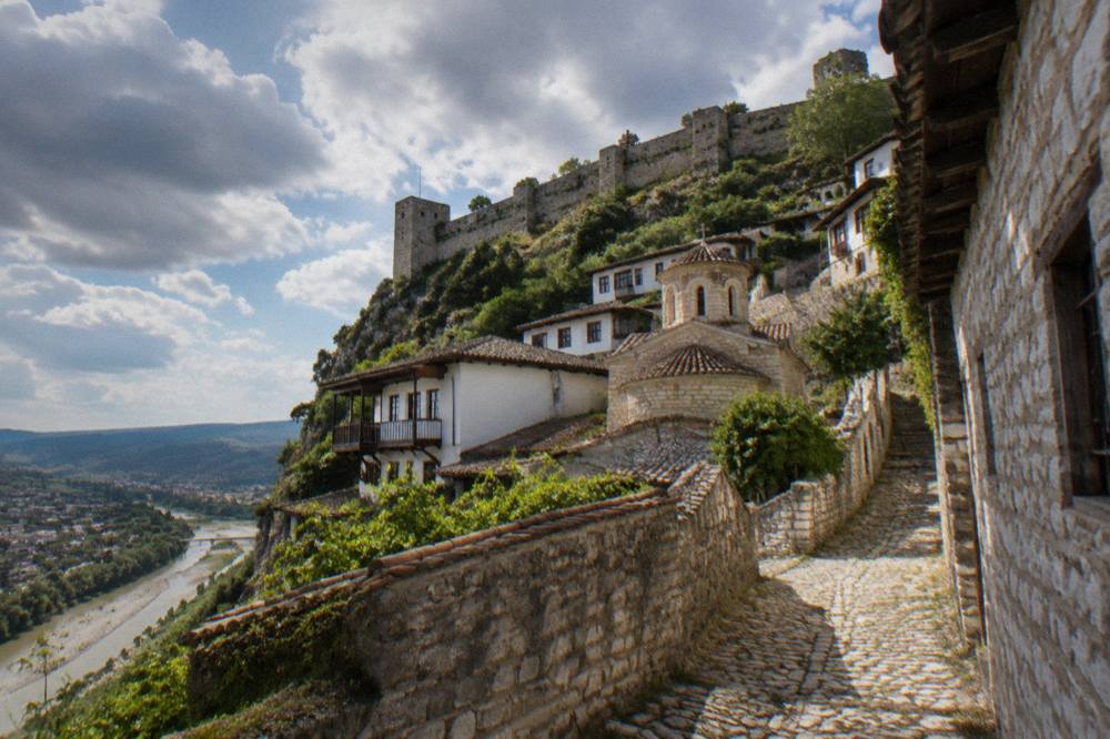 A small church building set among stone and whitewashed houses in a Berat lane